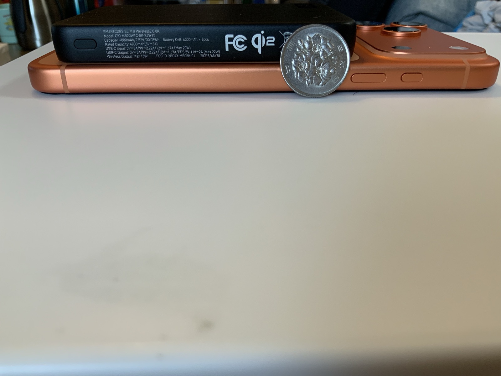 スマートフォンの背面にマグネット装着したCIO SMARTCOBY SLIM II 8Kを横から見た薄さ比較。100円玉を立てかけたスケール感